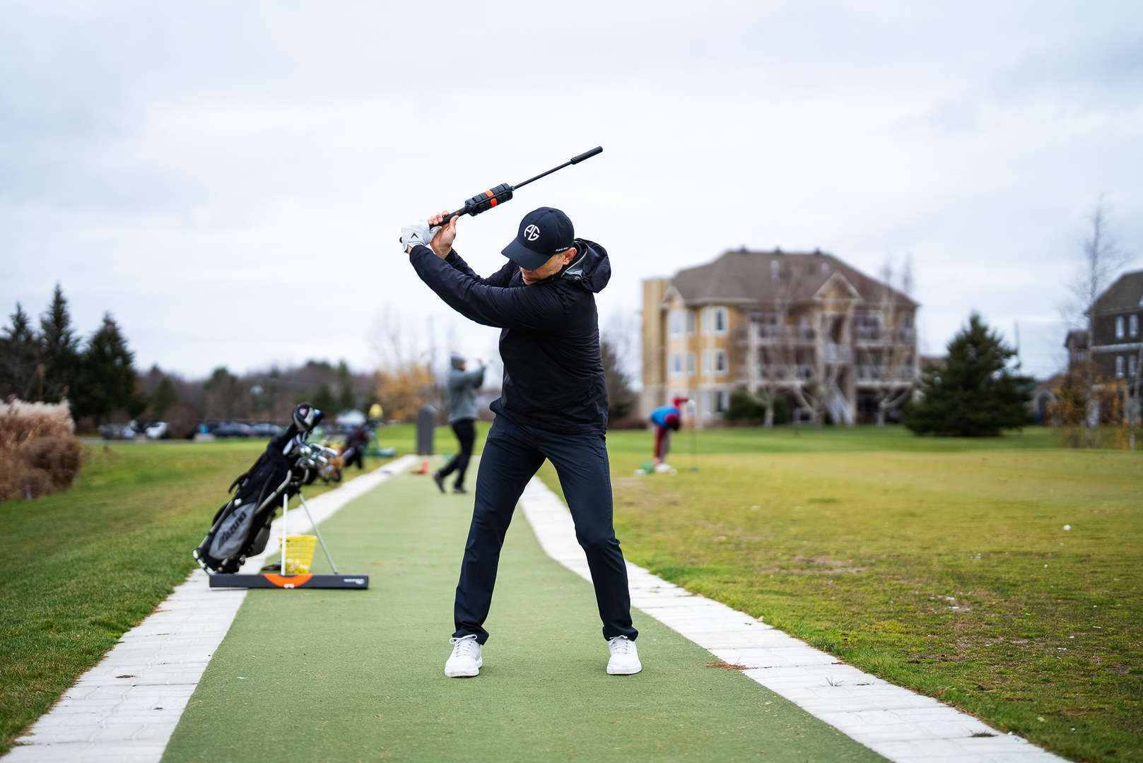 Golfer at the top of the backswing using the ONE Club Trainer on an outdoor driving range